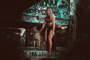 Cane corso w towarzystwie opiekunki na tle miejskiej ściany