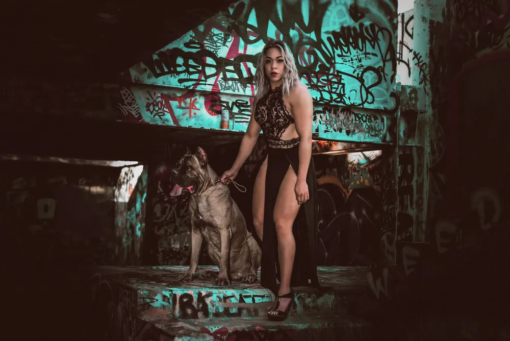Cane corso w towarzystwie opiekunki na tle miejskiej ściany
